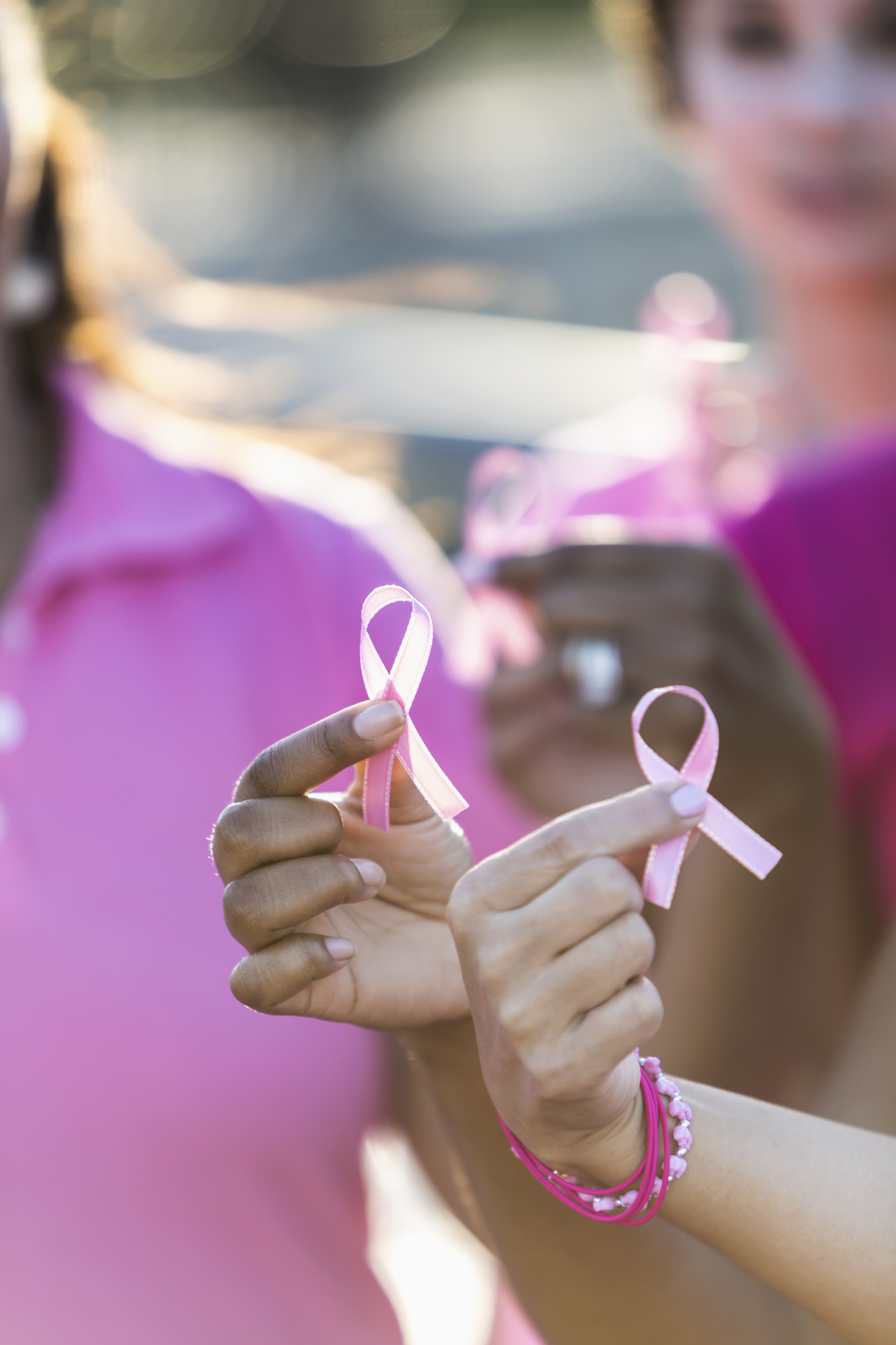Multiracial hands holding breast cancer awareness ribbon